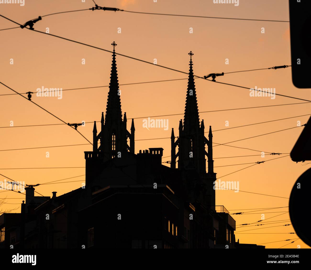 Silhouetten einer Kirche mit gotischer Architektur und elektrischen Kabeln Bei Sonnenuntergang Stockfoto