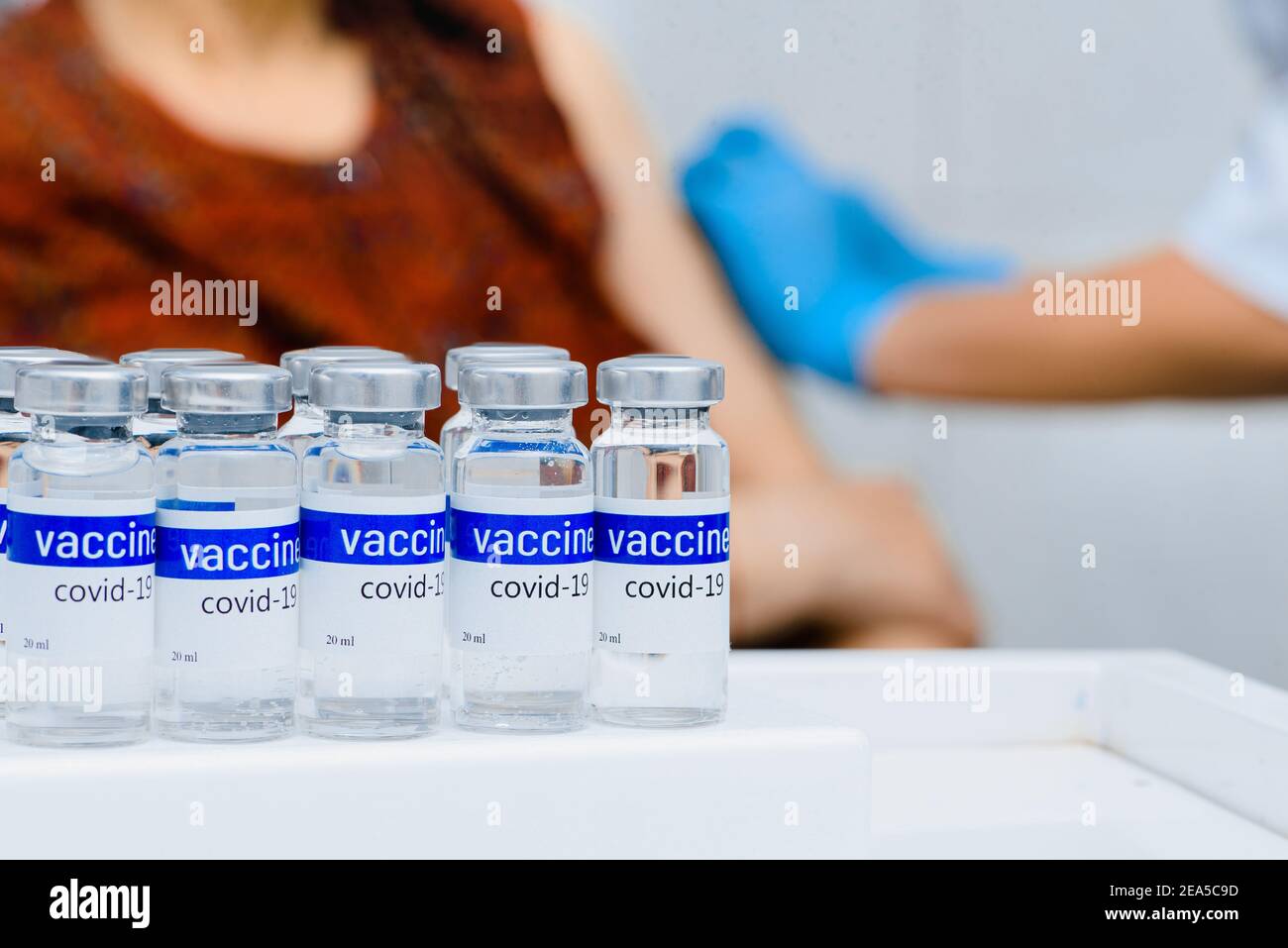 Reihe von Impffläschchen Arzt impft eine ältere Frau trägt Stockfoto