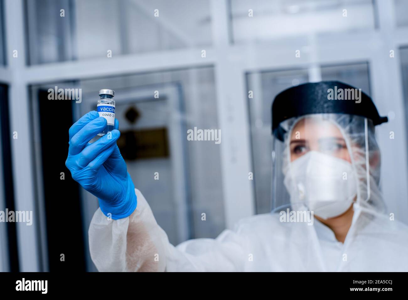 Laborant in Schutzanzug und Maske hält Impfstoff in Ausgestreckte Hand Stockfoto