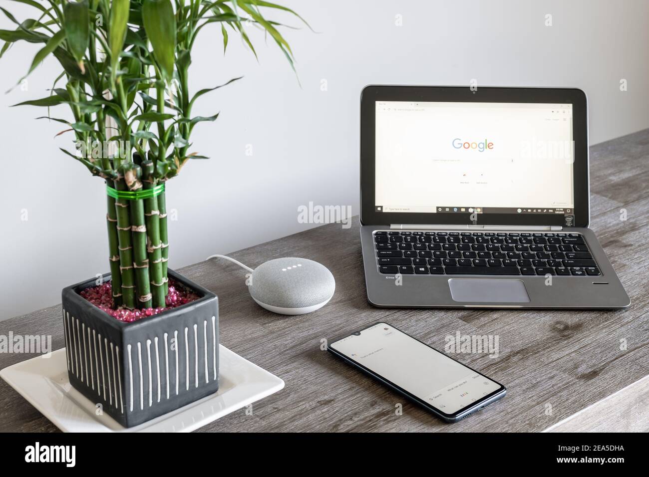 Adelaide, Australien - 7. Juli 2019: Google Home Mini mit HP Laptop mit Windows 10 und Handy auf Tisch nebeneinander eingerichtet Stockfoto