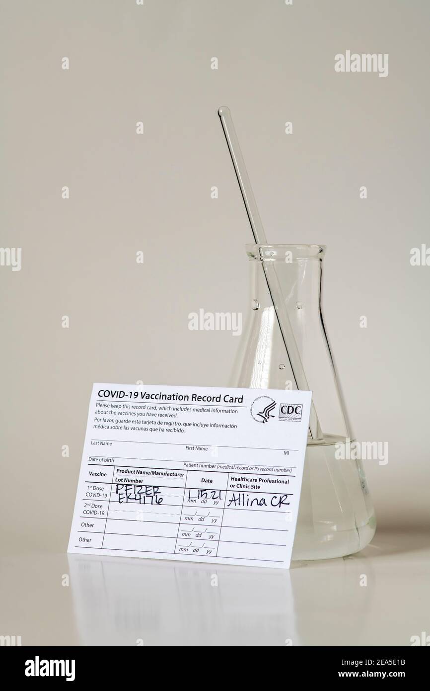 Pfizer Covid-19 Impfpass mit pharmazeutischem Becher. Stockfoto