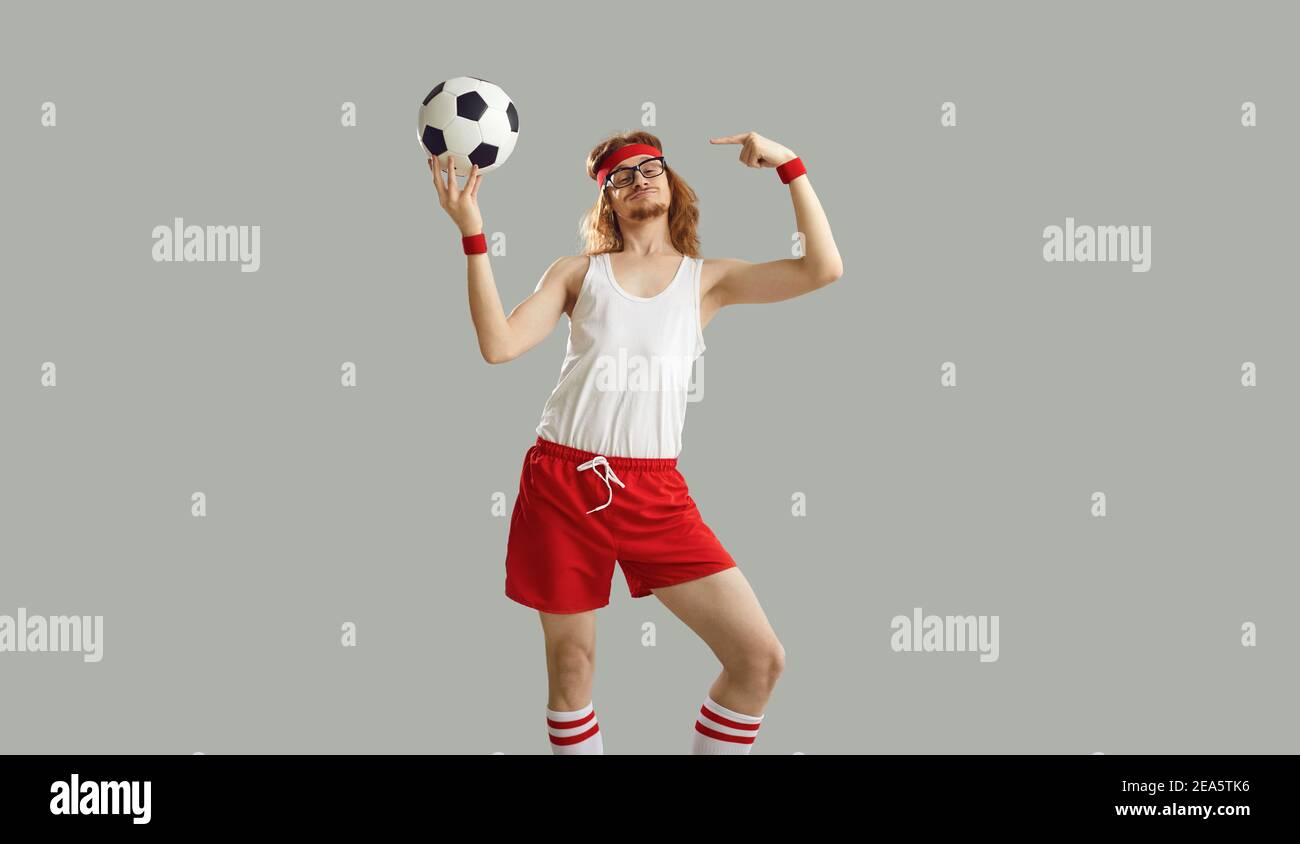 Lustiger Nerdy Mann in Brille und Sportswear hält Fußball Und stolz auf sich selbst zeigend Stockfoto
