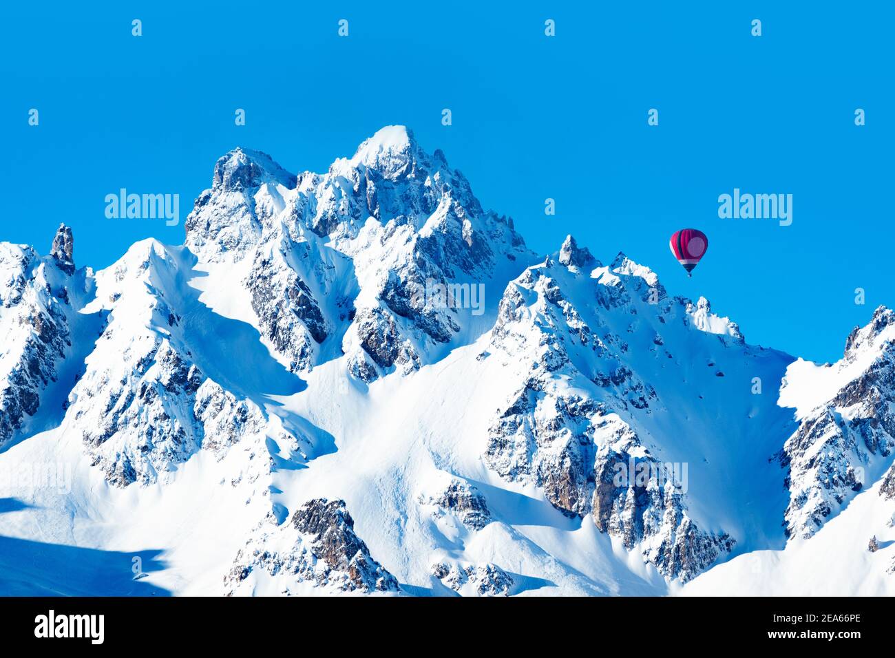 Farbenfroher Heißluftballon über hohen Berggipfeln der französischen Alpen An sonnigen Tag Stockfoto