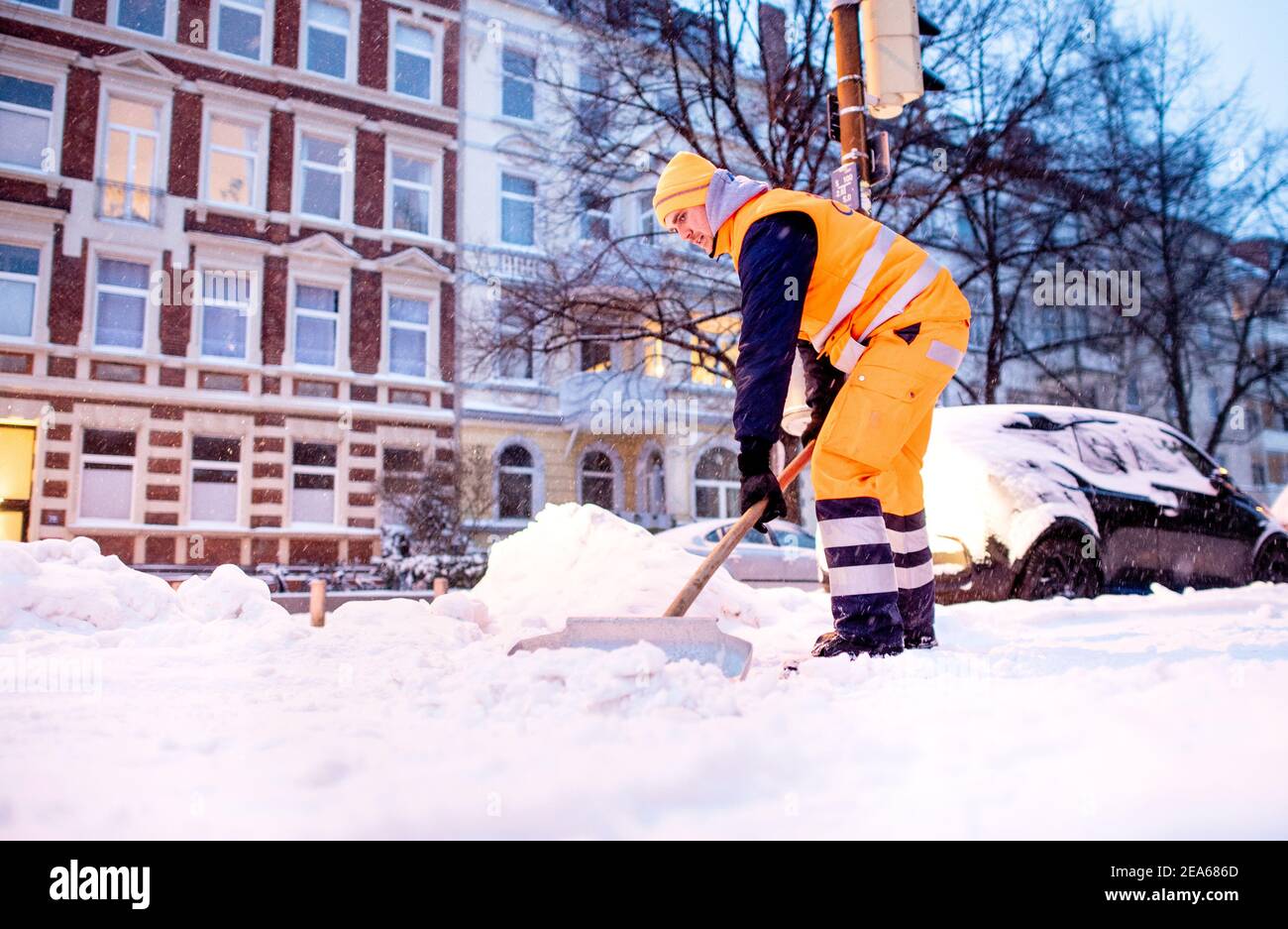 Hannover, Deutschland. Februar 2021, 08th. Ein Mitarbeiter des Aha Zweckverbandes Abfallwirtschaft Region Hannover räumt bei Schneefall auf einem Bürgersteig in Südstadt Schnee und Eis. Quelle: Hauke-Christian Dittrich/dpa/Alamy Live News Stockfoto