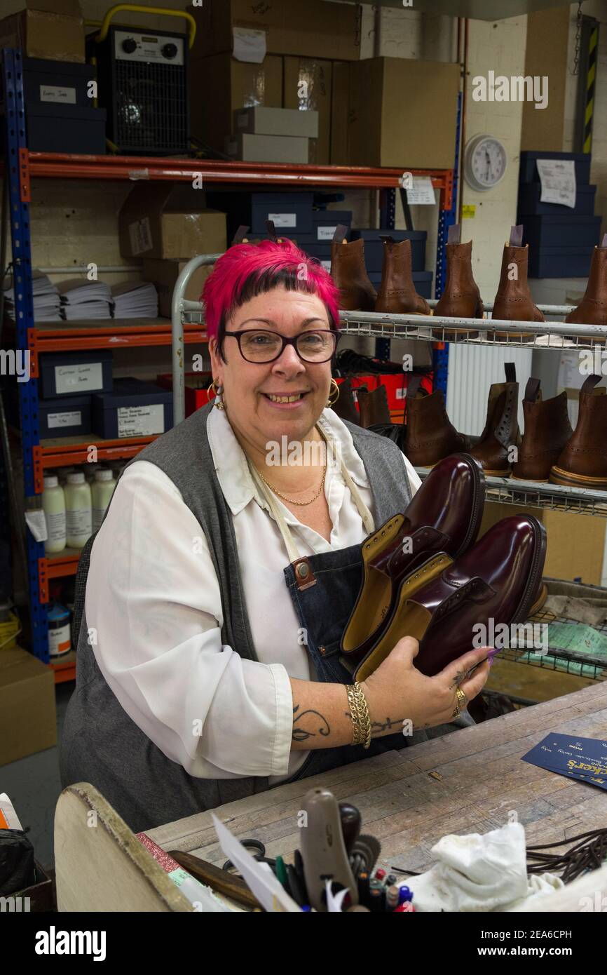 Eine Schuharbeiterin bringt den letzten Schliff für ein Paar handgefertigte Herrenschuhe, Trickers Schuhfabrik, Northampton, Großbritannien Stockfoto