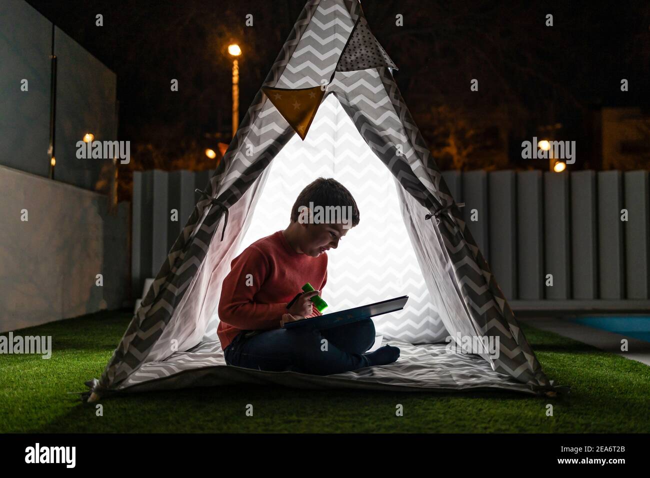 Kleines Kind liest ein Buch auf einem indischen Zelt bei Nacht Stockfoto