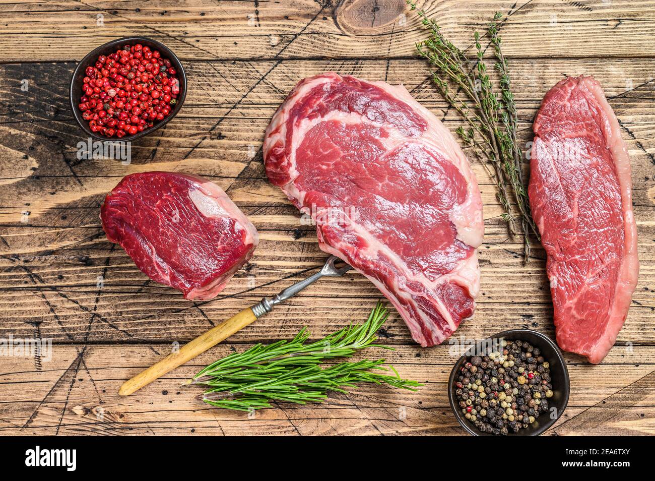 Frisch roh prime schwarz angus Rindfleisch Steaks Filet Mignon, Rib Eye oder Cowboy, Striploin. Holzhintergrund. Draufsicht Stockfoto