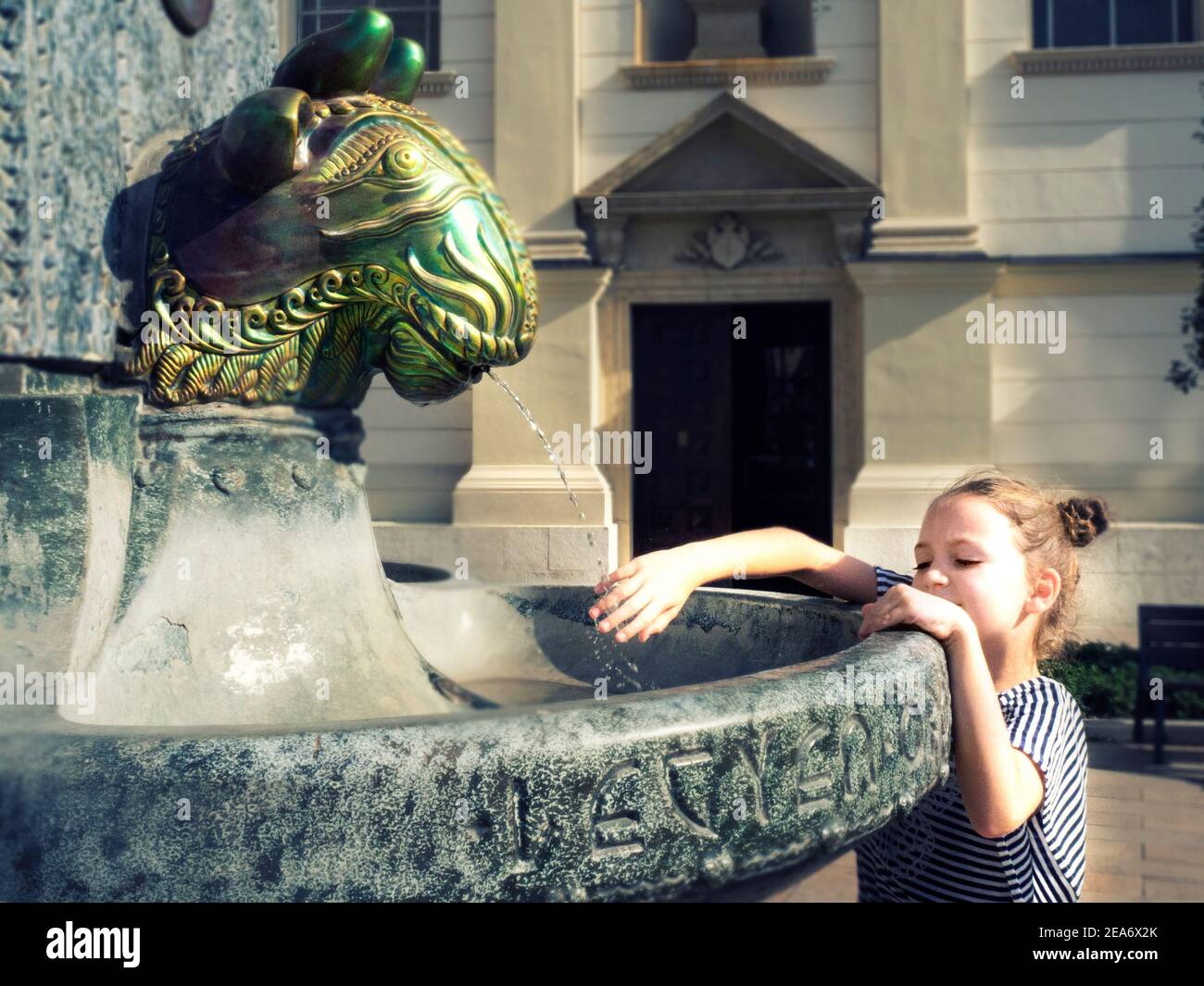 Mädchen, das an einem Brunnen steht und ihre Hand unter fließendem Wasser hält, Ungarn Stockfoto