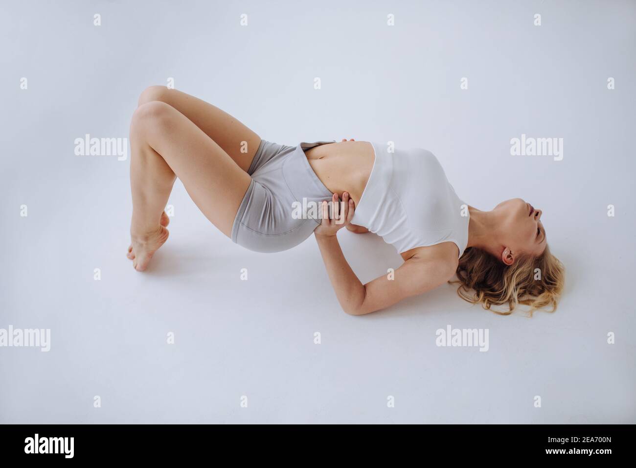 Frau in legerer Sportkleidung liegend auf ihrem Rücken lehnend auf Ihre Ellbogen Stockfoto