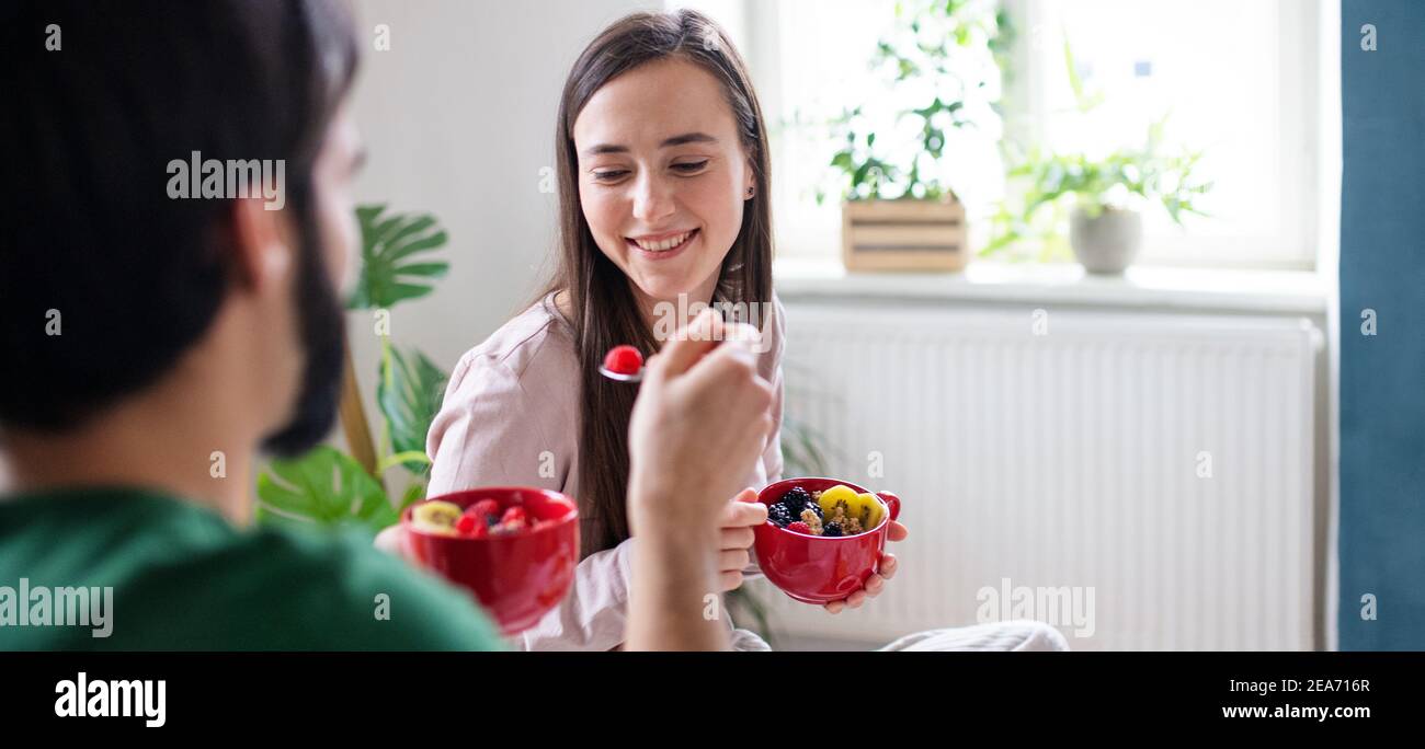 Junges Paar in der Liebe essen gesundes Frühstück auf dem Bett drinnen zu Hause. Stockfoto