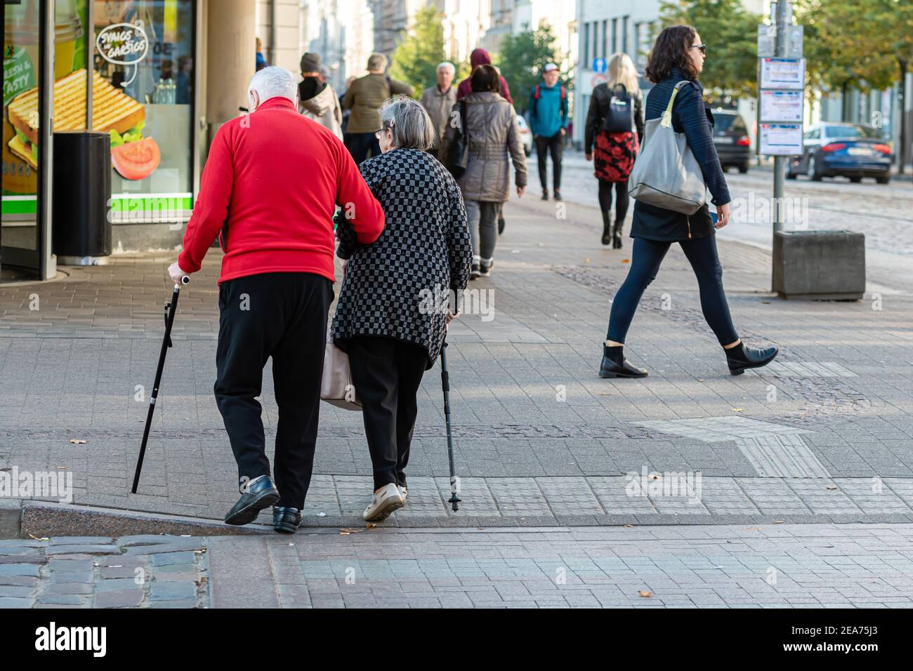 Riga, Lettland - 7. Oktober 2020: Ein paar ältere Menschen mit einem Spazierstock gehen über die Straße Stockfoto