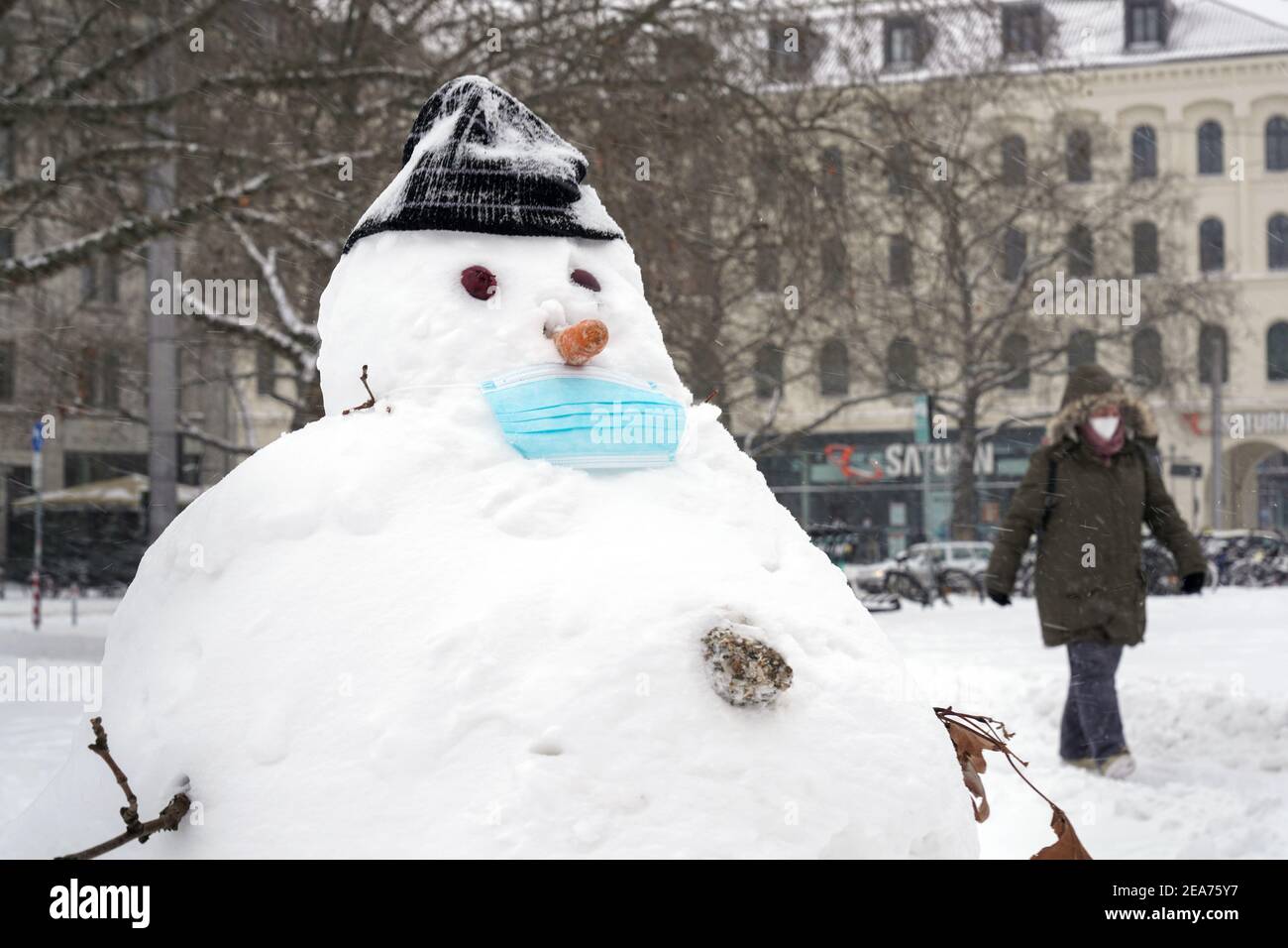 Hannover, 08,02.2021: Wintereinbruch in Norddeutschland, Schneemann mit einer medizinischen Maske auf dem Ernst-August-Platz in Hannover --- Hannover, 8th. Februar 2021: Winter in Norddeutschland, Schneemann mit medizinischer Maske auf dem Ernst-August-Platz in Hannover Stockfoto