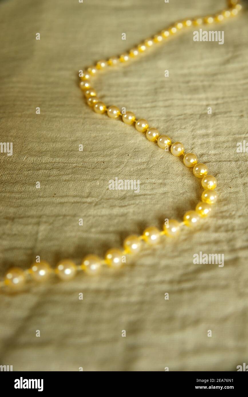 Perlenkette, die eine S-Form auf einem Musselin bildet Stoff Stockfoto