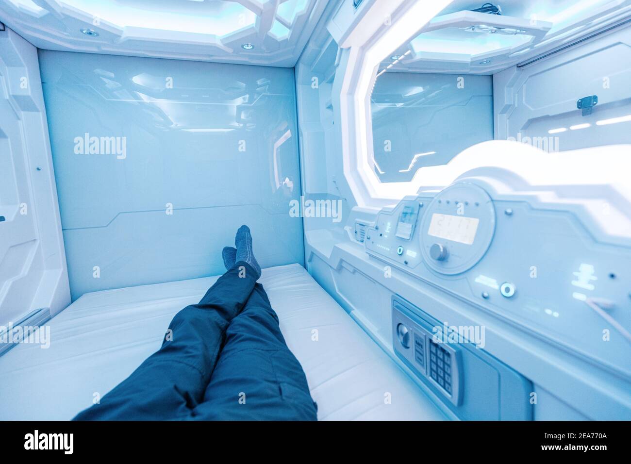 Ein Mann ruht und schläft in einer Kapsel Hotelansicht von innen. Das Innere ähnelt einer Kryokapsel in einem Raumschiff Stockfoto