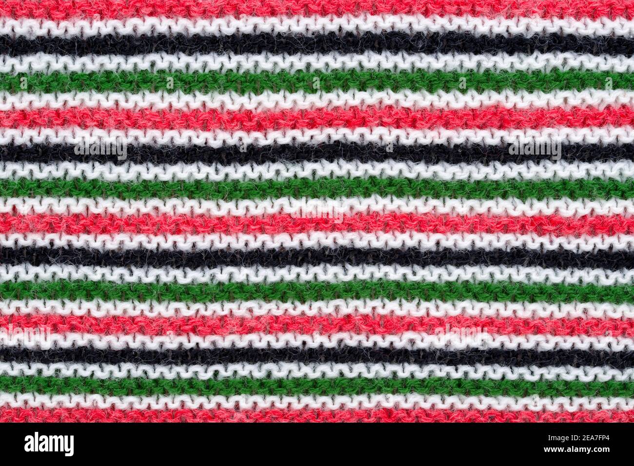 Nahaufnahme von Hand gestricktem Wollmuster in rot, weiß, schwarz und grün. Stockfoto