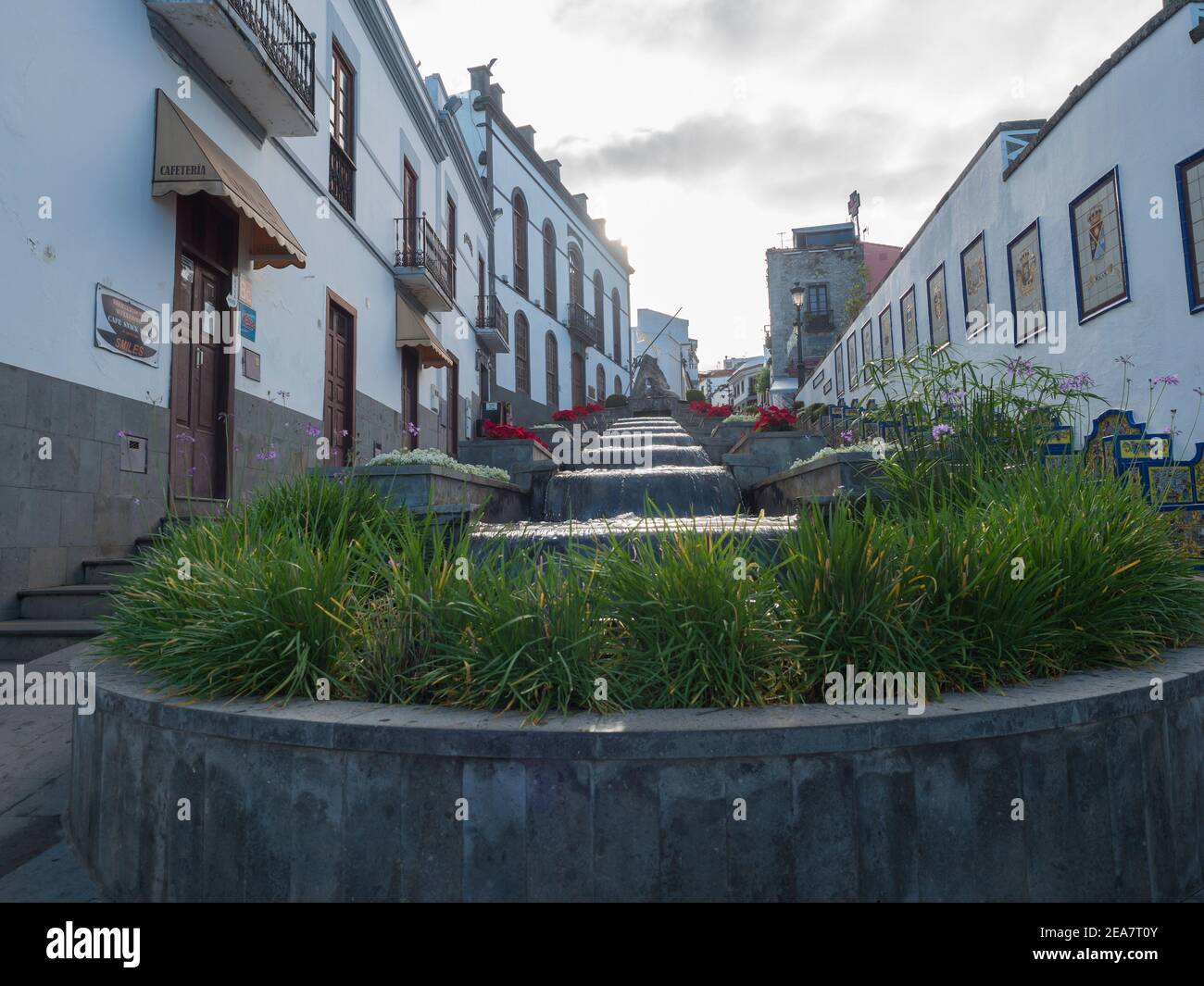 Firgas, Gran Canaria, Kanarische Inseln, Spanien 13. Dezember 2020: Blick auf die Straße Paseo de Gran Canaria mit Wasserfall Brunnen, Blumen und Keramik Stockfoto