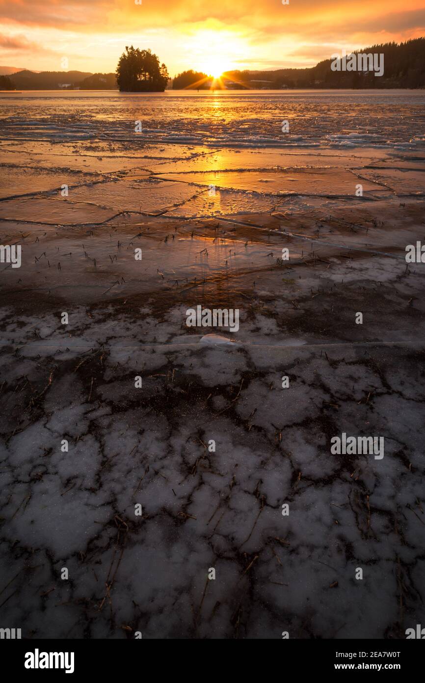 Eisige gefrorene Ufer des Sees in Sonnenuntergang Zeit. Jonsvatnet See bei Trondheim in Norwegen. Wunderschöne Sonnenuntergangsfarben am Himmel und Wolken. Eismuster und Stockfoto