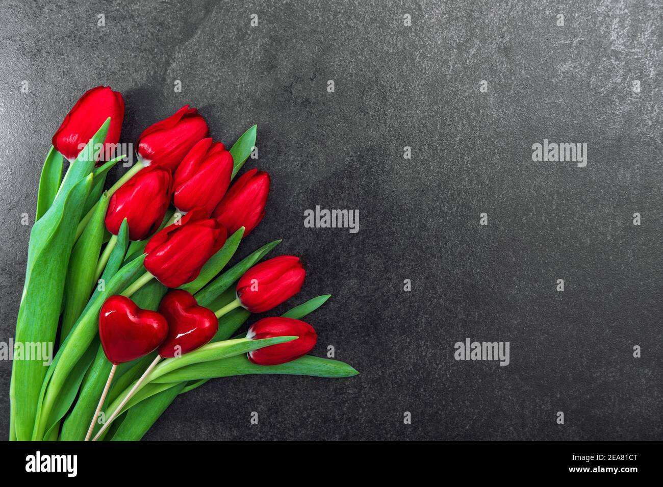 Rote Herzen Tulpenblüten auf dunklem Hintergrund. Dekoration zum Valentinstag Stockfoto