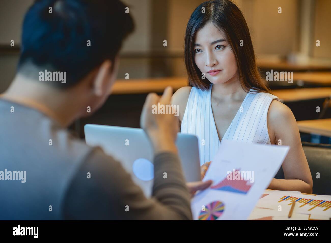 Rückansicht der Furious Chef schimpfen asiatische junge Geschäftsfrau in Casual Anzug von Punkt zu ihrem Gesicht über Leistung und KPI im modernen Büro, Business Stockfoto