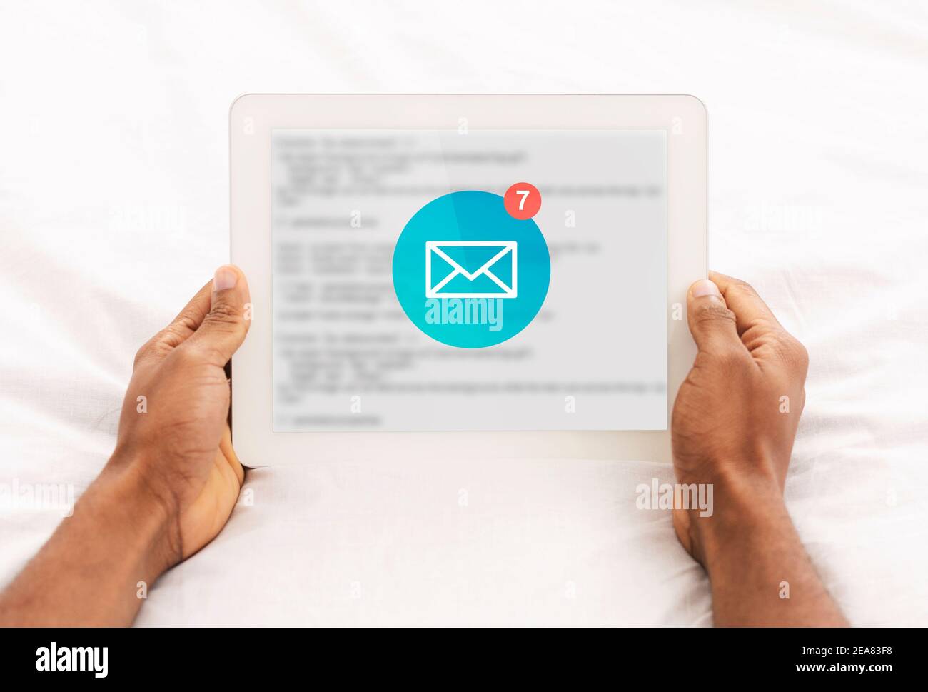 Afrikanischer Mann Liest E-Mail-Nachrichten Auf Tablet Liegend Im Schlafzimmer Stockfoto