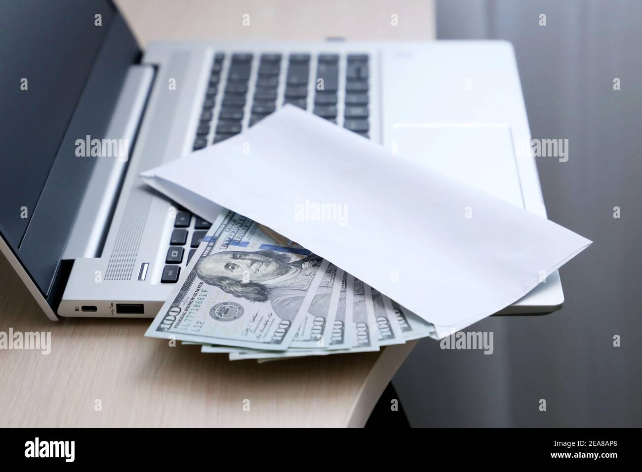 Umschlag mit US-Dollar auf Laptop-Tastatur. Löhne, Bonus oder Bestechung Konzept Stockfoto