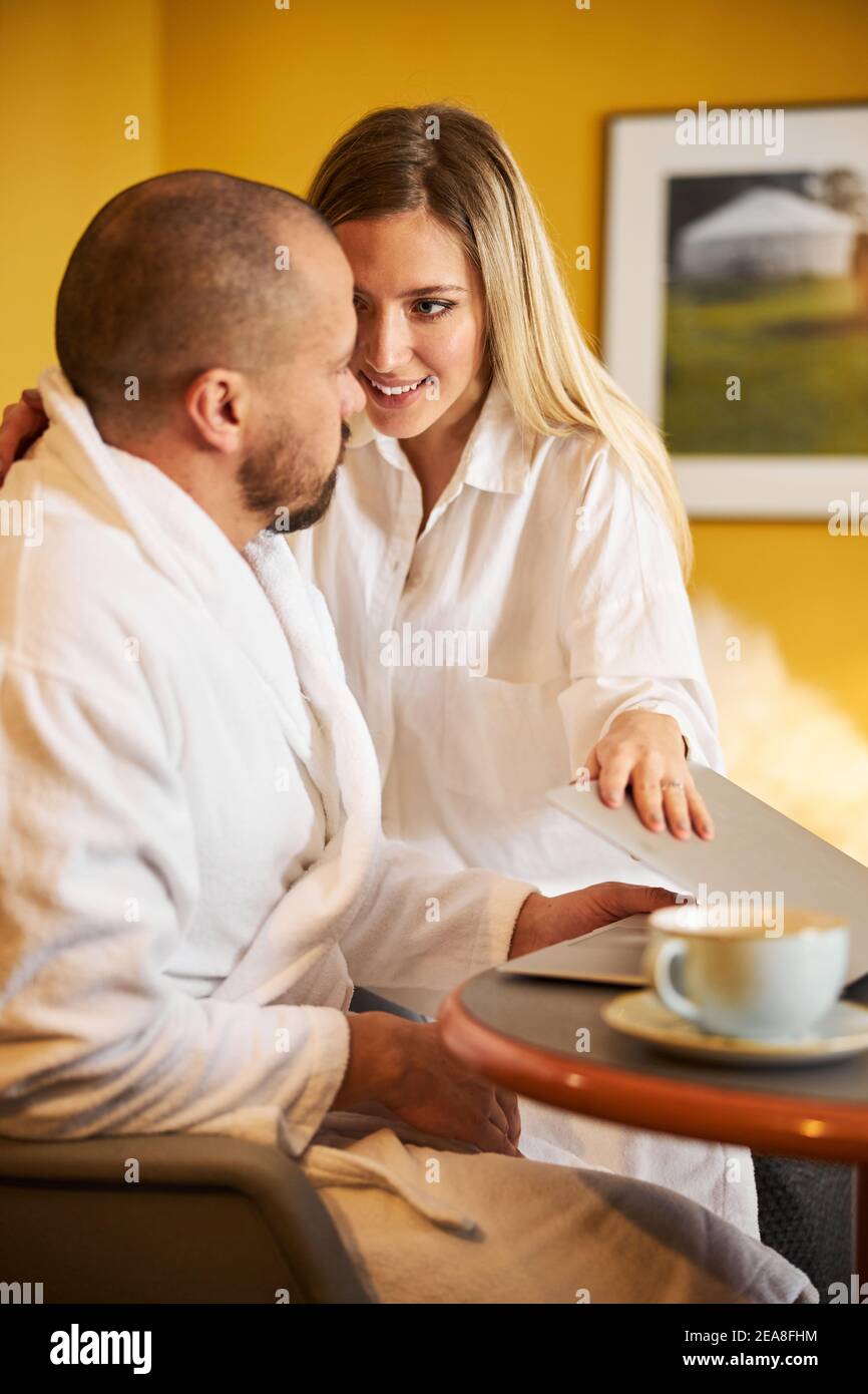 Junge Frau sucht ihren beschäftigten Ehemann Aufmerksamkeit Stockfoto