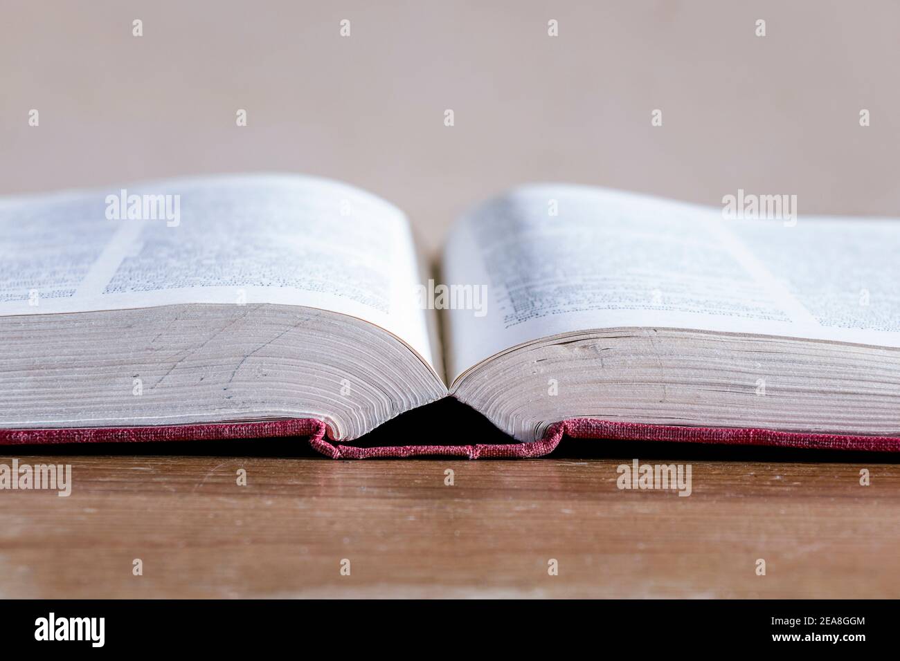 Nahaufnahme eines offenen Hardback-Nachschlagebuchs auf einem alten Holztisch Stockfoto