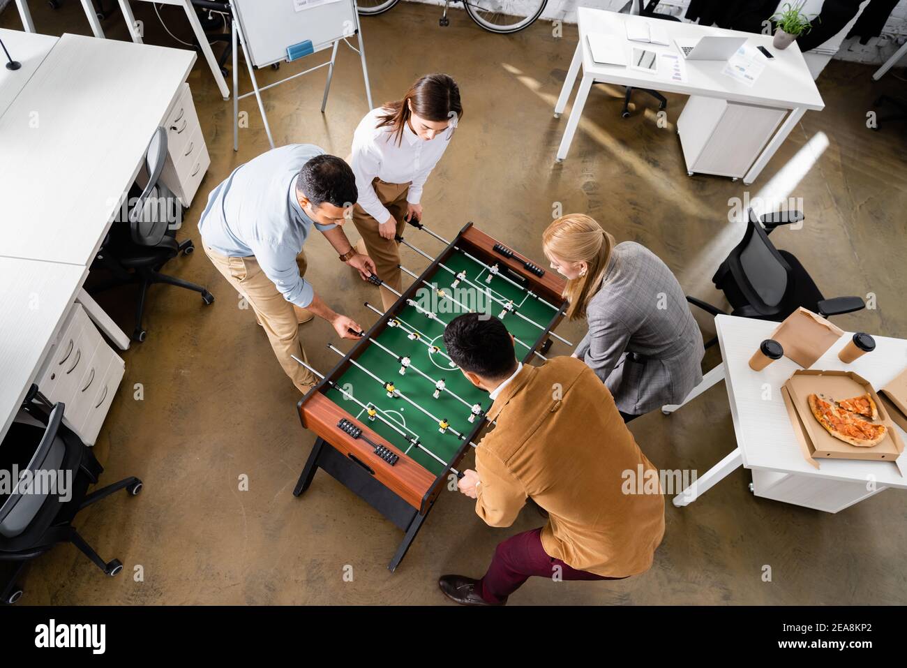 Overhead-Ansicht der multikulturellen Geschäftsleute spielen Tischfußball während Mittagessen im Büro Stockfoto