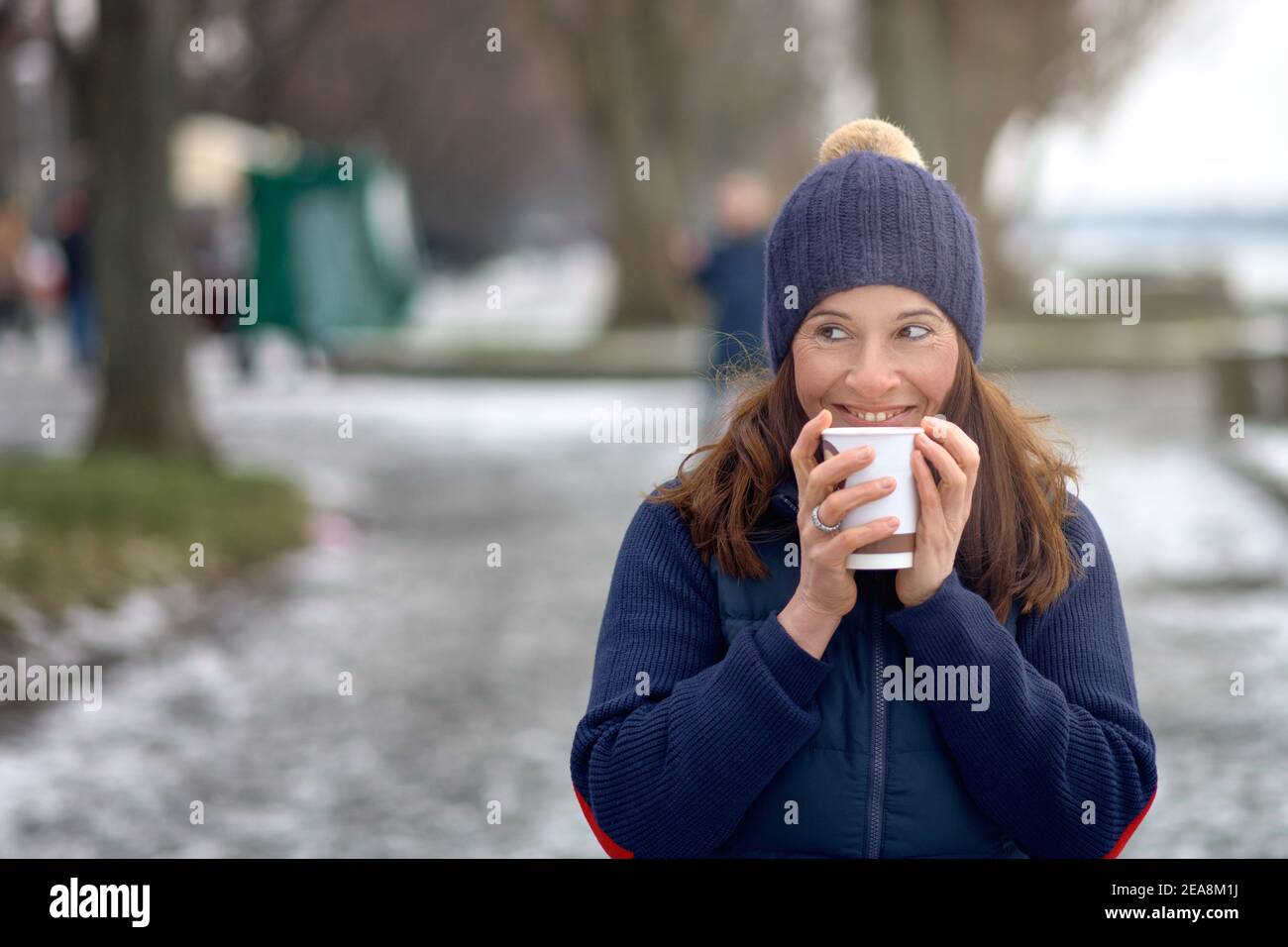 Glückliche Brünette Frau mittleren Alters gehen für einen Spaziergang und trinken Ein Kaffee zum gehen Stockfoto