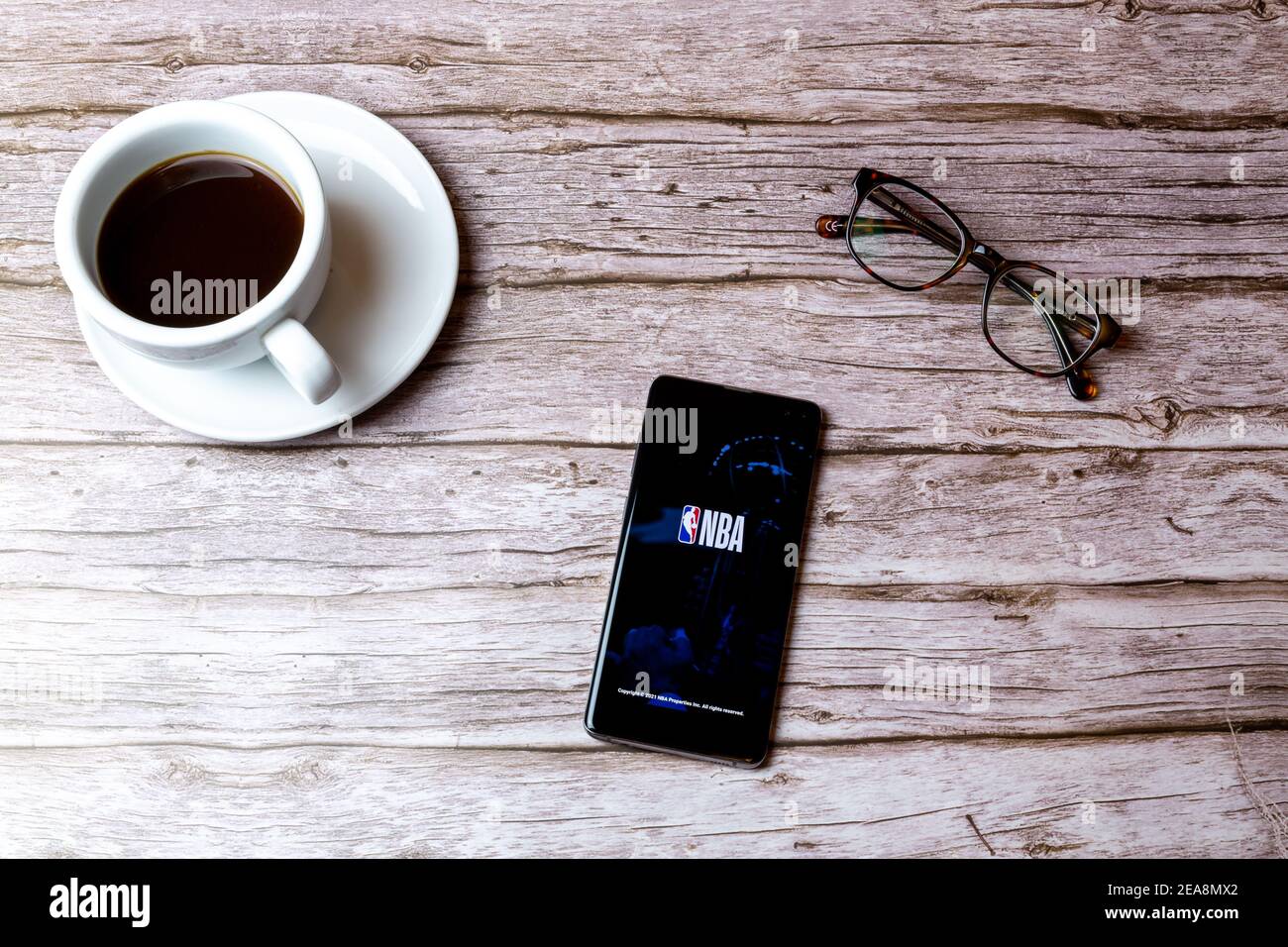 Ein Handy oder Handy auf einem Holz gelegt Tisch mit der NBA-App geöffnet neben einem Kaffee Und Brille Stockfoto