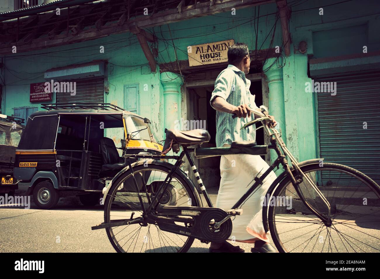 Mann mit Fahrrad vorbei Tuk Tuk Taxi, Fort Cochin, Kerala, Indien Stockfoto