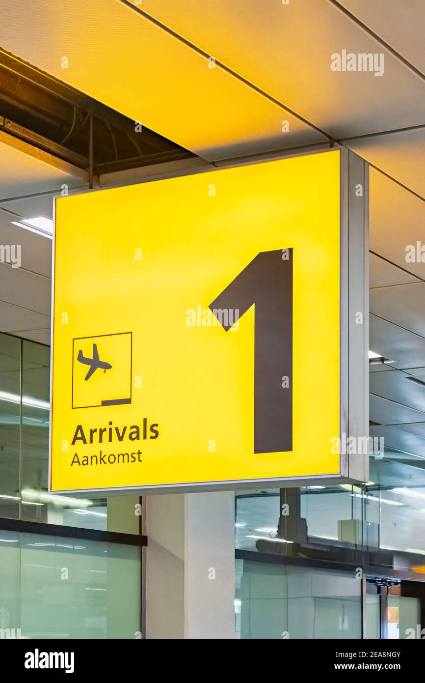 Ankunftsschild für den gelben Flughafen in Niederländisch-Gelb mit dem Text "Ankunft" auf englisch und niederländisch Stockfoto