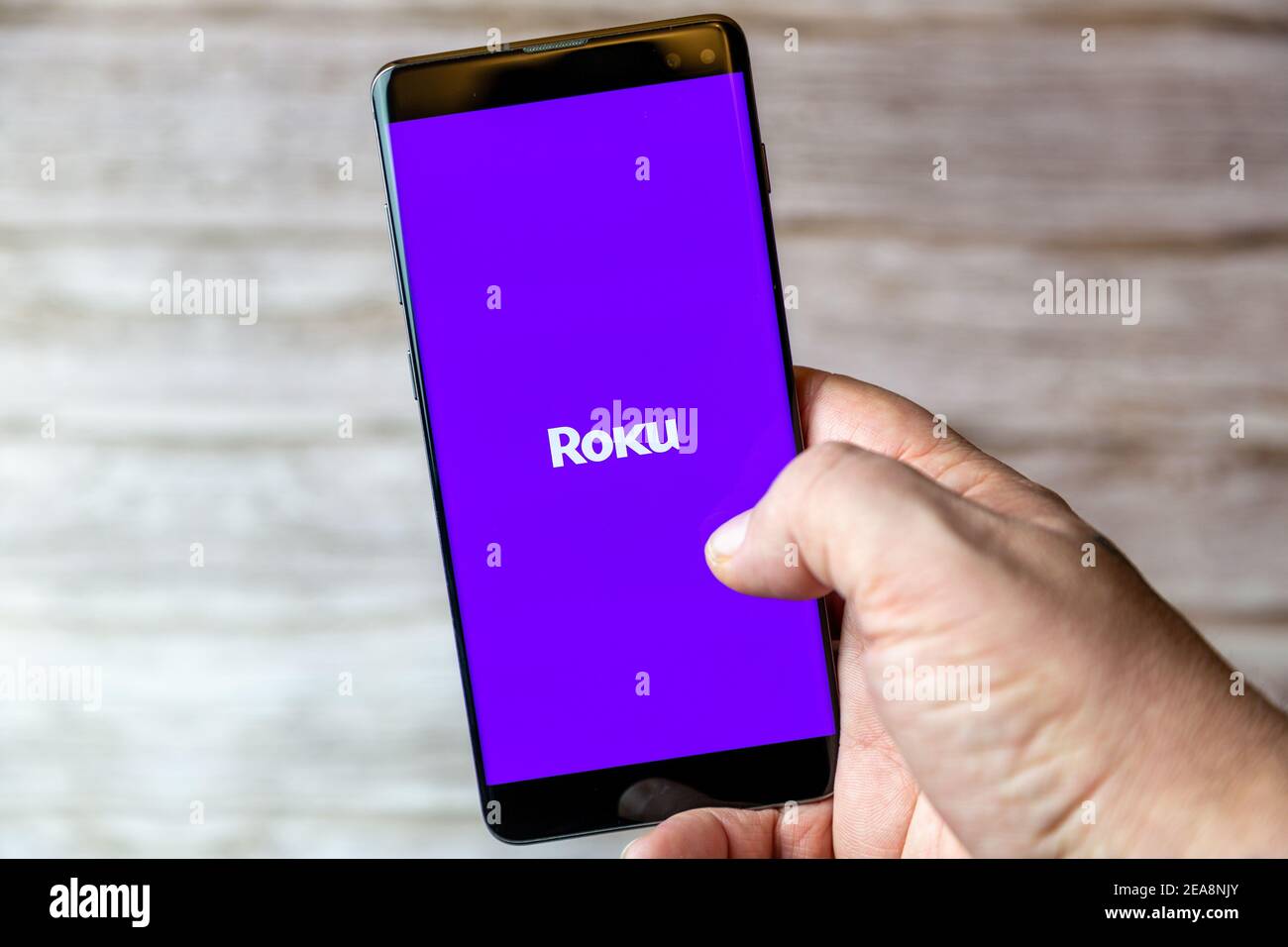 Ein Mobiltelefon oder Mobiltelefon, das in einem gehalten wird Hand mit der Roku TV App auf dem Bildschirm geöffnet Stockfoto