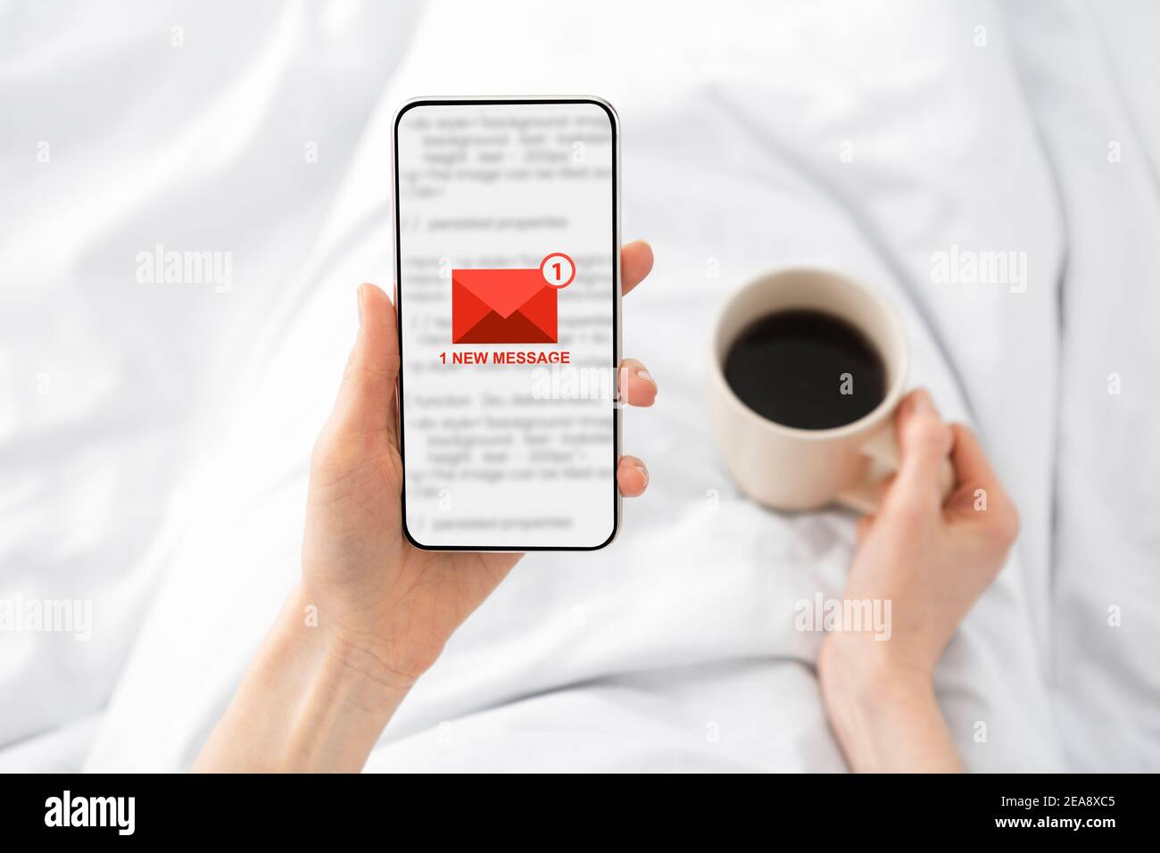 Frau hält Telefon mit E-Mail-Nachricht im Bett liegend innen Stockfoto