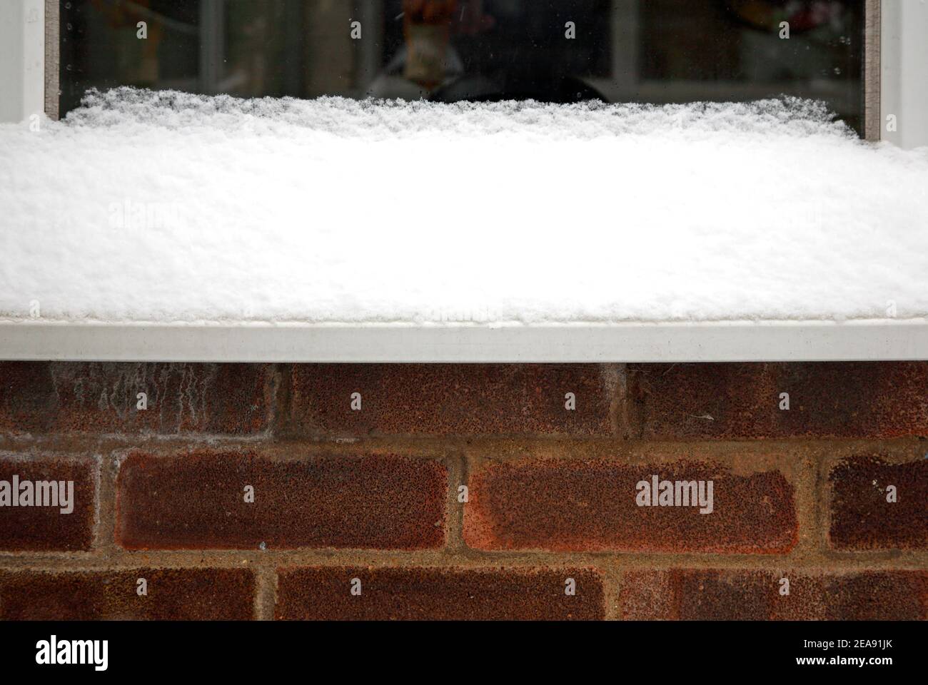 Eine Ansammlung von Schnee auf einer Fensterbank während einer Periode des kalten Wetters im Winter in Hellesdon, Norfolk, England, Vereinigtes Königreich. Stockfoto