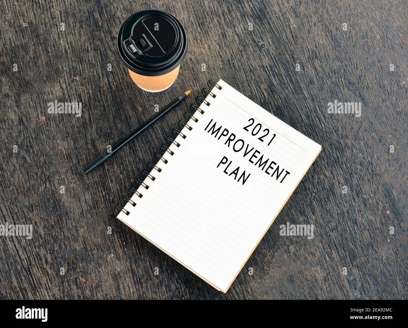 Text auf Notizblock mit Einweg-Kaffeetasse und Stift auf Holztisch Stockfoto