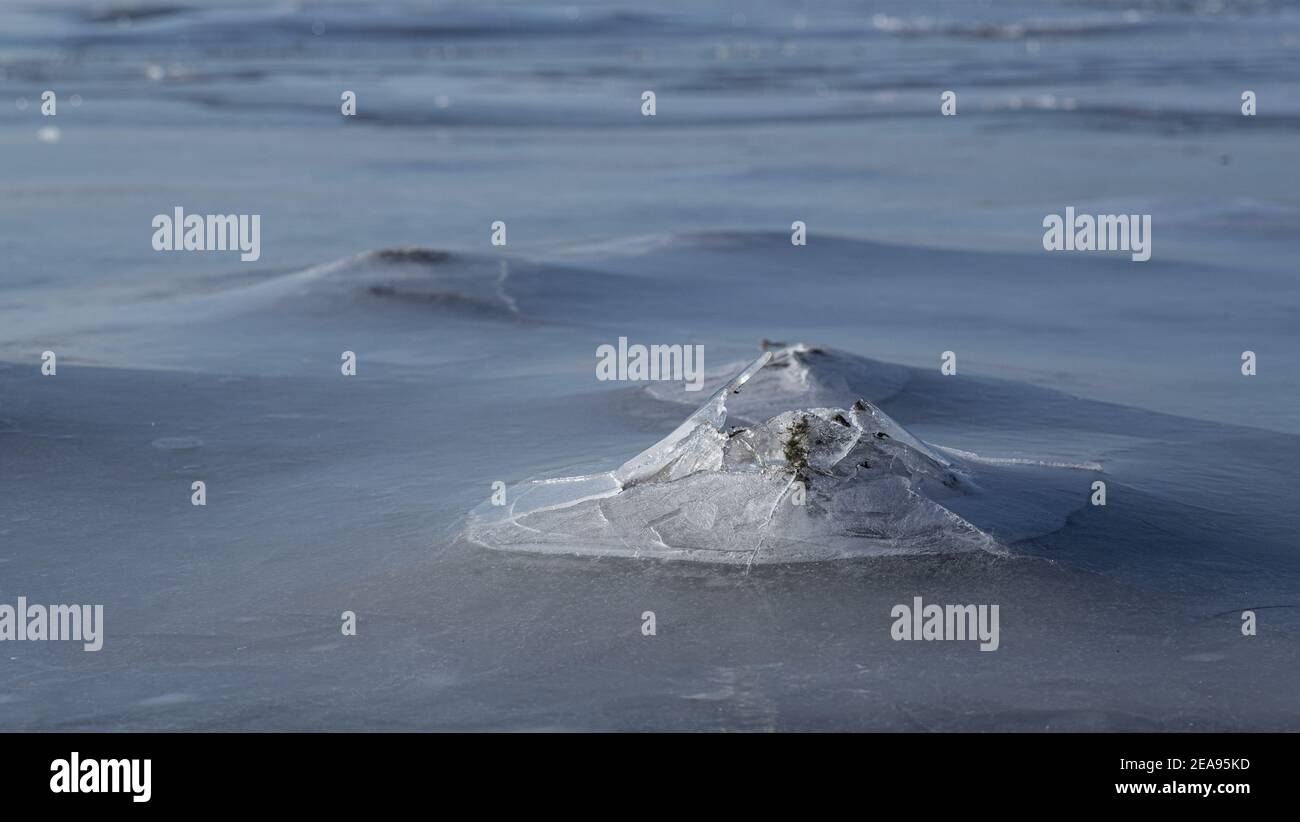 Das Wasser erstarrte bei Sonnenuntergang über einem Felsen im Meer In Skandinavien Stockfoto