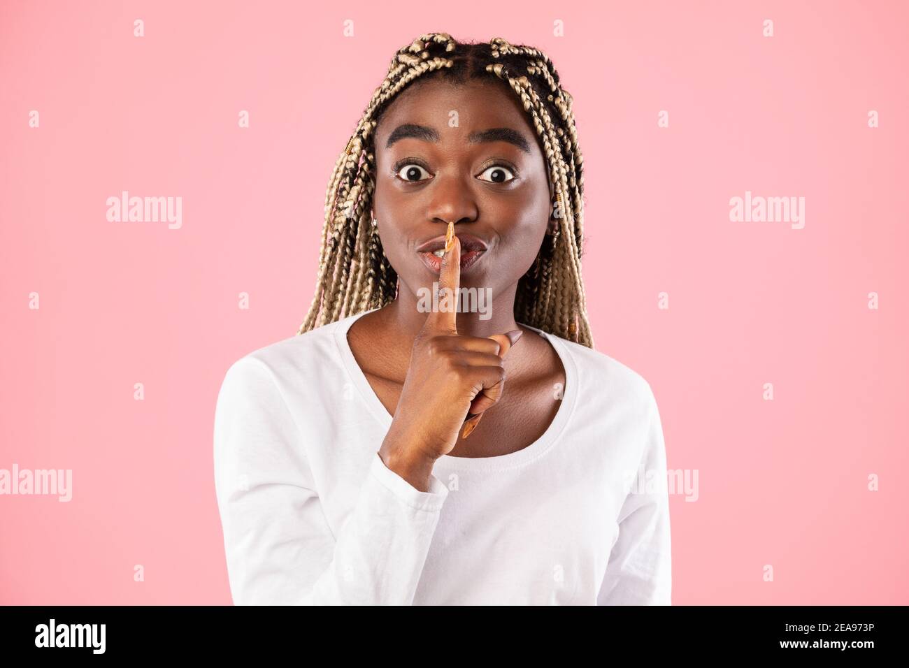 Schwarze Frau, die Finger auf die Lippen stampft und ein Zeichen für die Stille macht Stockfoto