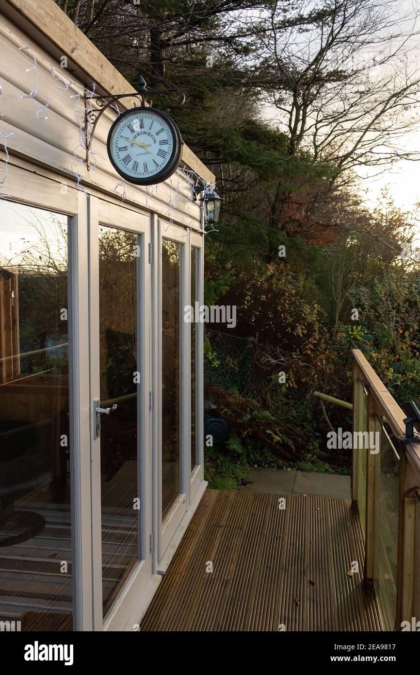 Kirkcudbright, Schottland - 24. Dezember 2020: Eine Kensington London Uhr hängt über einem Gartenbüro in der späten Nachmittagssonne im Winter Stockfoto