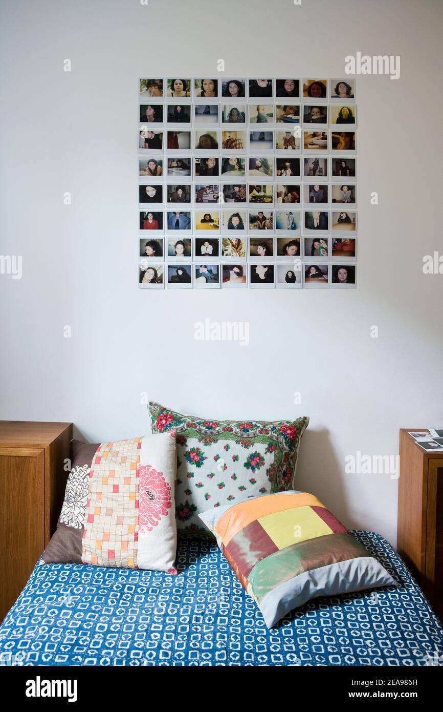 Porträt von Polaroids, an einer weißen Wand, hinter dem Bett, mit einer blauen Decke, bunte Kissen, getrimmte Möbel, symbolisches Bild Stockfoto