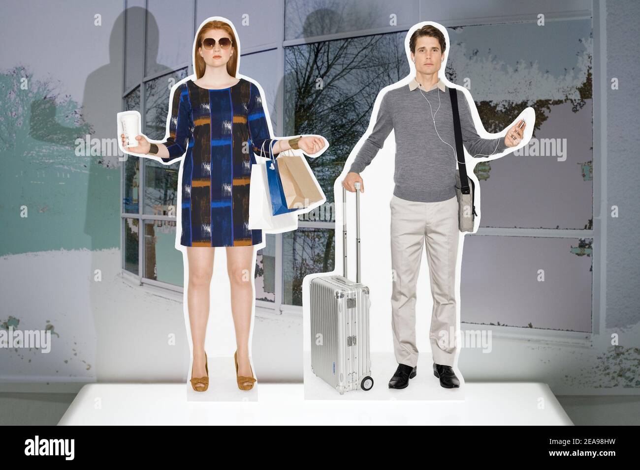 Mann und Frau, ausgeschnittene Figuren, Collage, Flugkoffer, Aktentasche, Coffee to go, Einkaufstaschen, Leuchtkasten, Handy, stilisierte Architektur Stockfoto