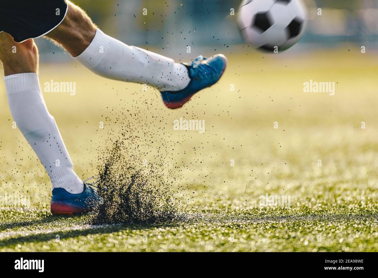 Erwachsene Fußballspieler tritt Ball an sonnigen Tag auf künstlichem Fußballplatz. Nahaufnahme Bild von Fußballer Beine und Sportball in Bewegung Stockfoto