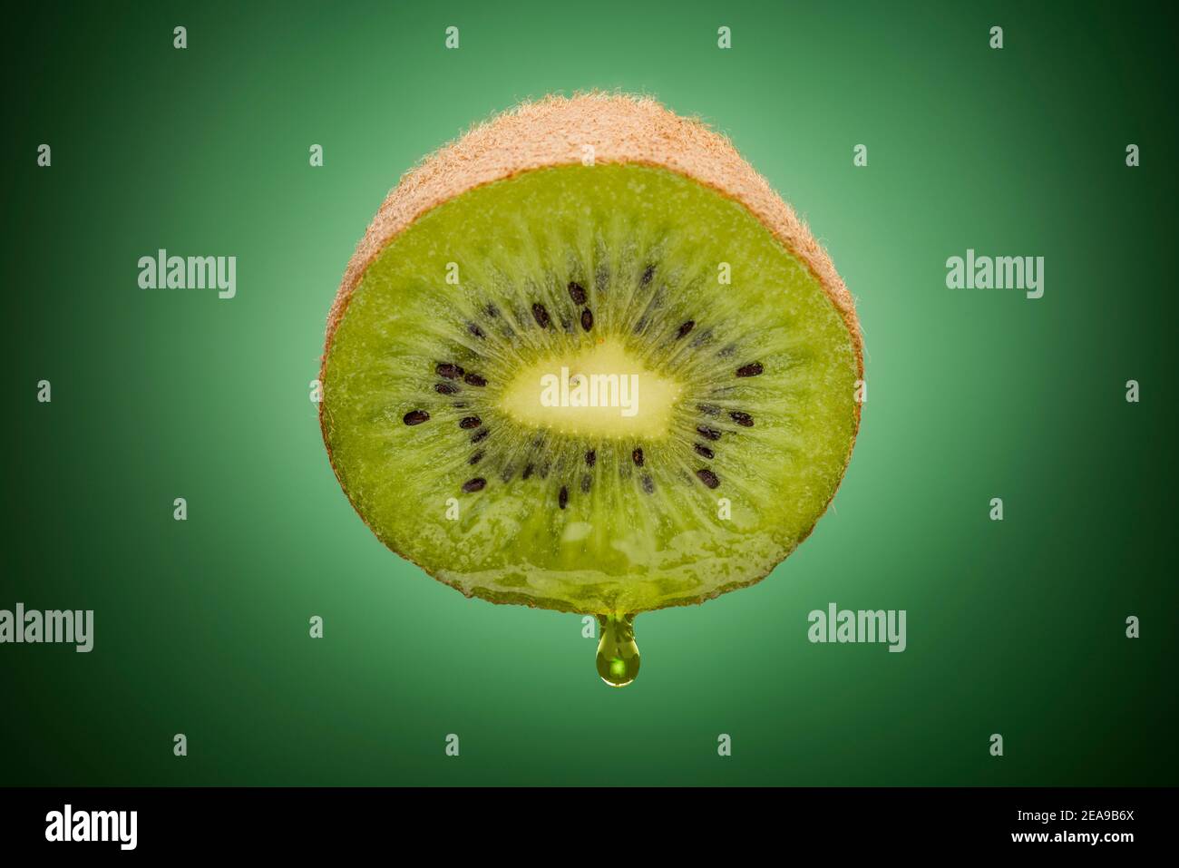 In Scheiben geschnittene Kiwi-Früchte mit tropfendem Saft auf grünem Hintergrund Stockfoto