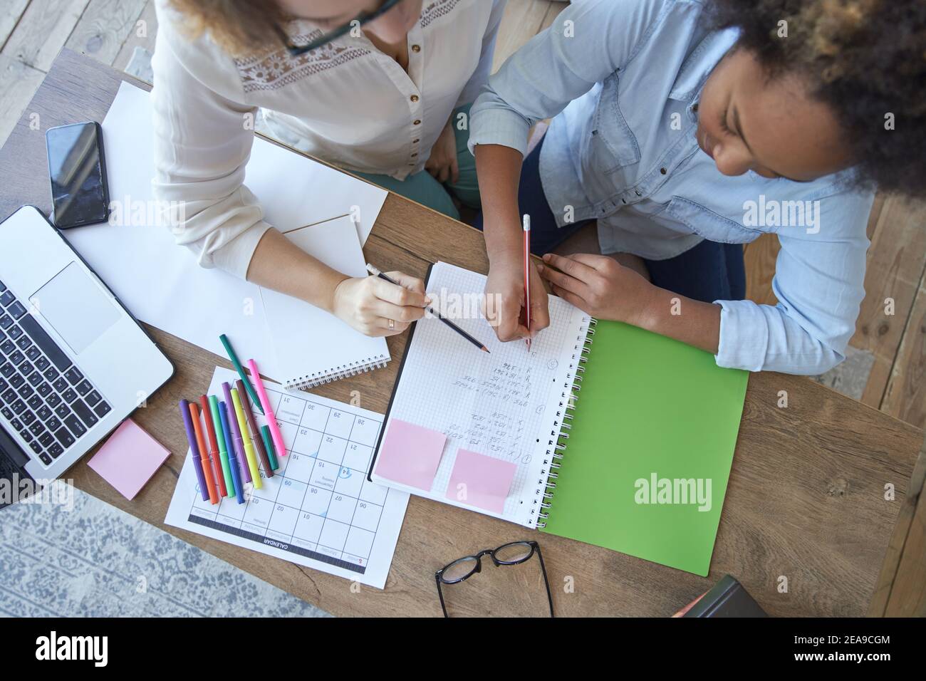 Draufsicht auf gemischte Rennen teen Mädchen tun Mathe Aufgabe, Schule Hausaufgaben zusammen mit Lehrerin im Wohnzimmer zu Hause Stockfoto