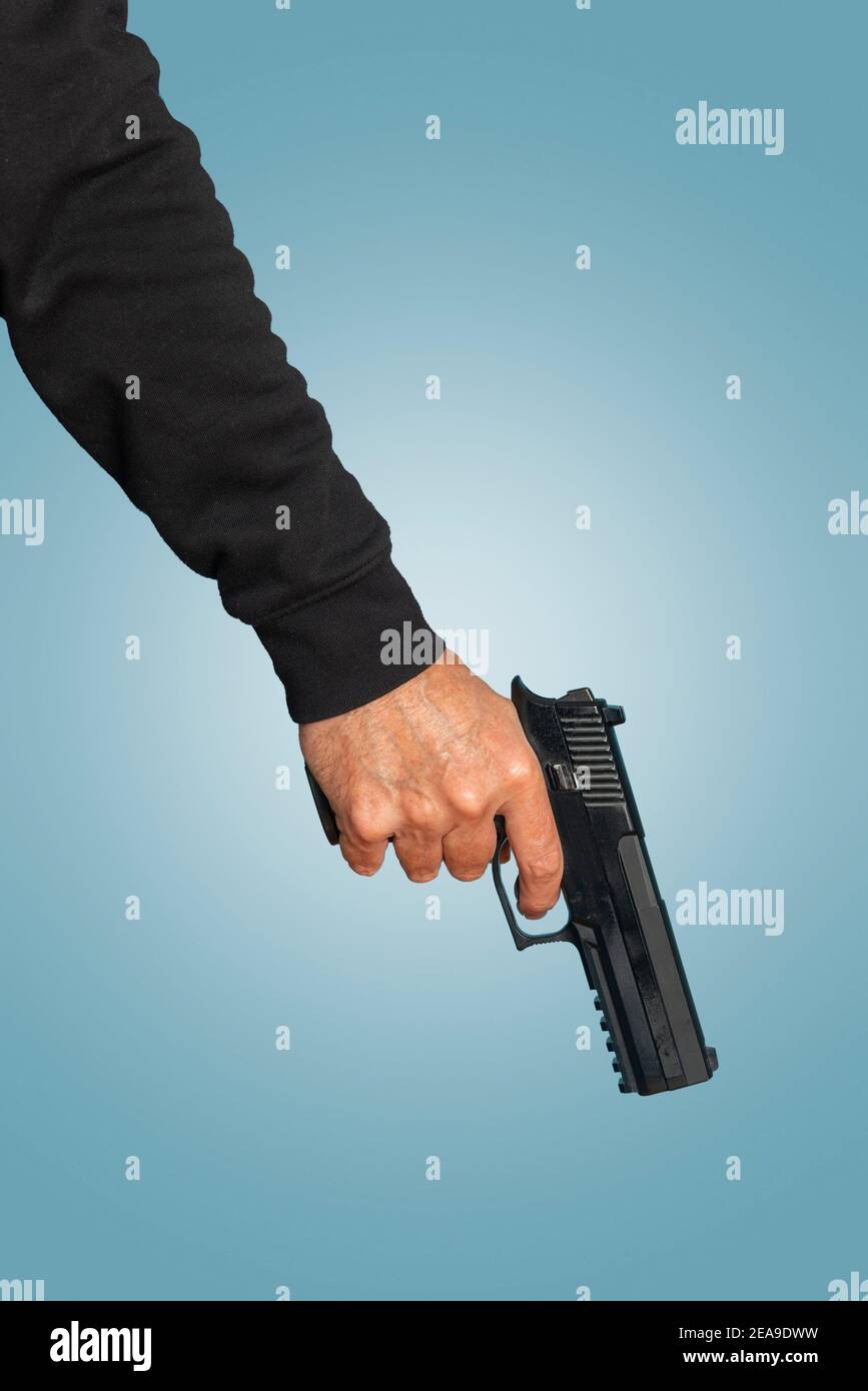 Hand mit Pistole, Pistole auf blauem Hintergrund. Stockfoto