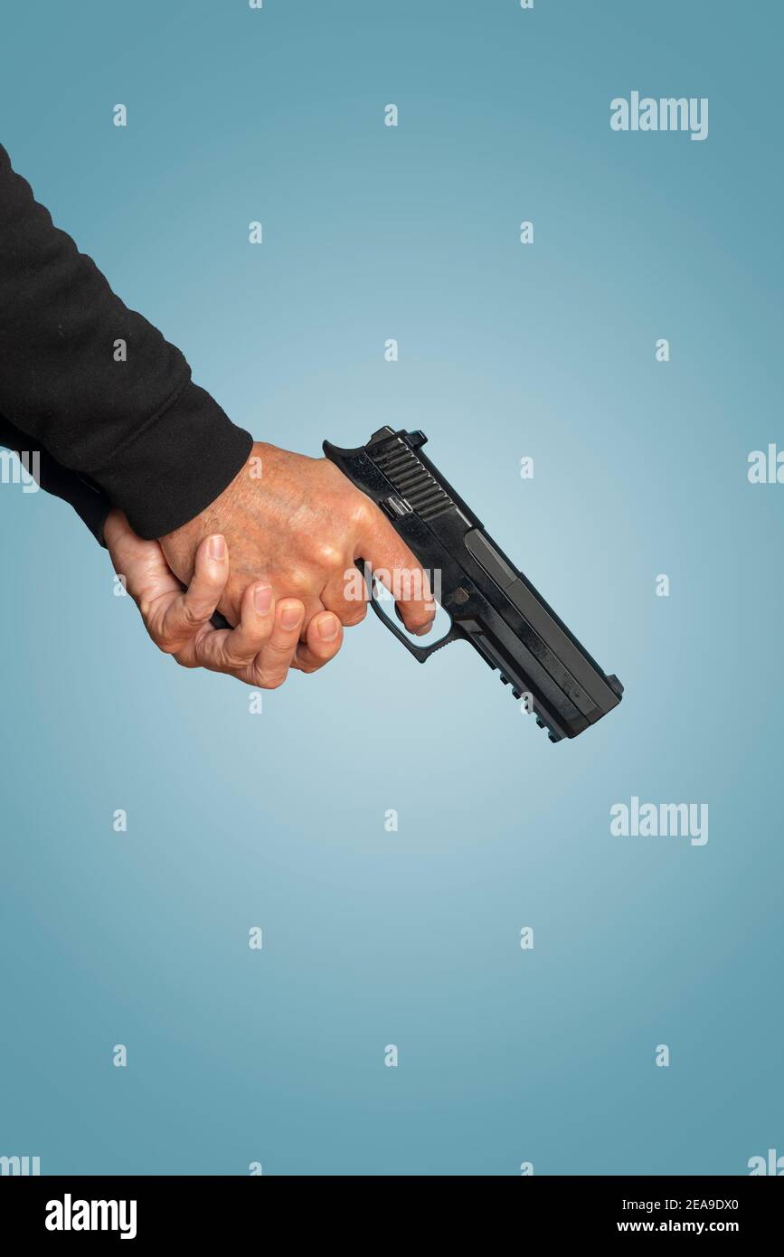 Zwei-Hand-Griff auf einer Pistole, Pistole auf blauem Hintergrund. Stockfoto