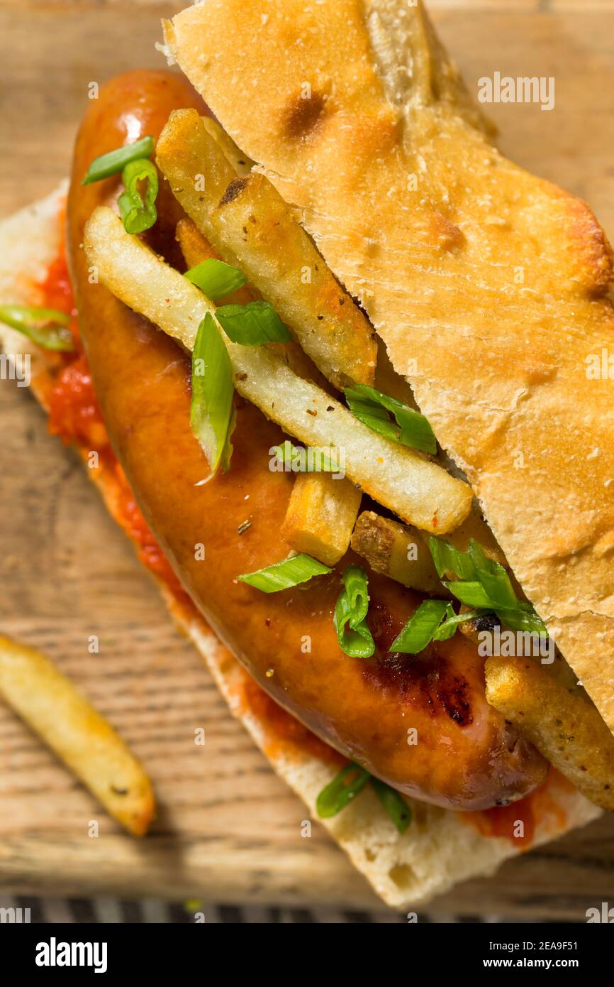 Hausgemachtes Merguez Frites Sausage Sandwich mit Harrisa auf einem Brötchen Stockfoto