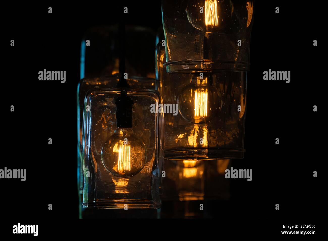 Einige rustikale Lichter im westlichen Stil hängen in einer Barstube. Die Filamente sind in vertikaler Anordnung und geben einen golden orangen Glanz ab. Stockfoto