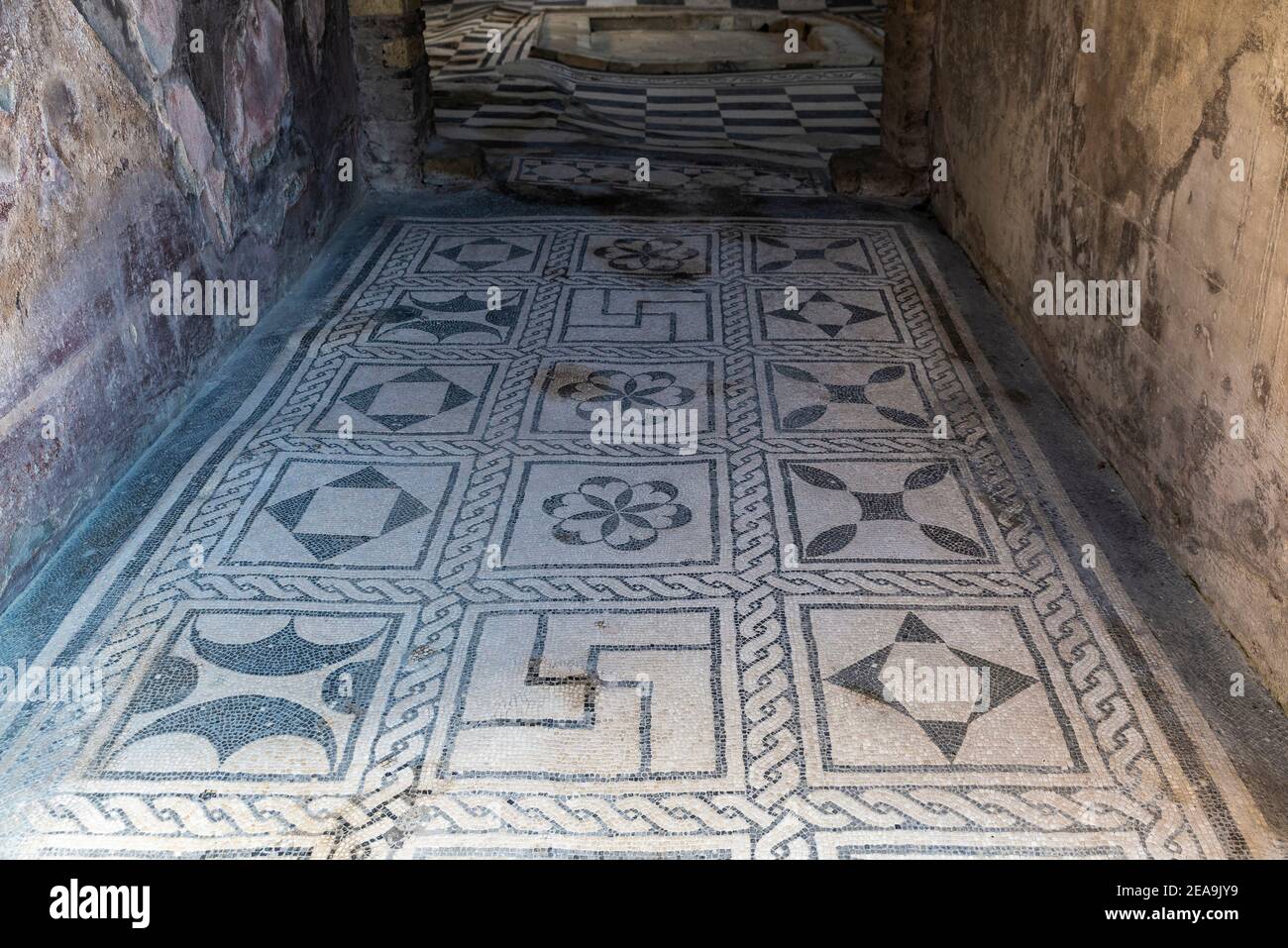 Das Innere eines Hauses mit seinem Boden mit einem Mosaik von Zeichen in den römischen Ruinen der alten archäologischen Stätte von Herculaneum in Ercolano geschmückt, Stockfoto