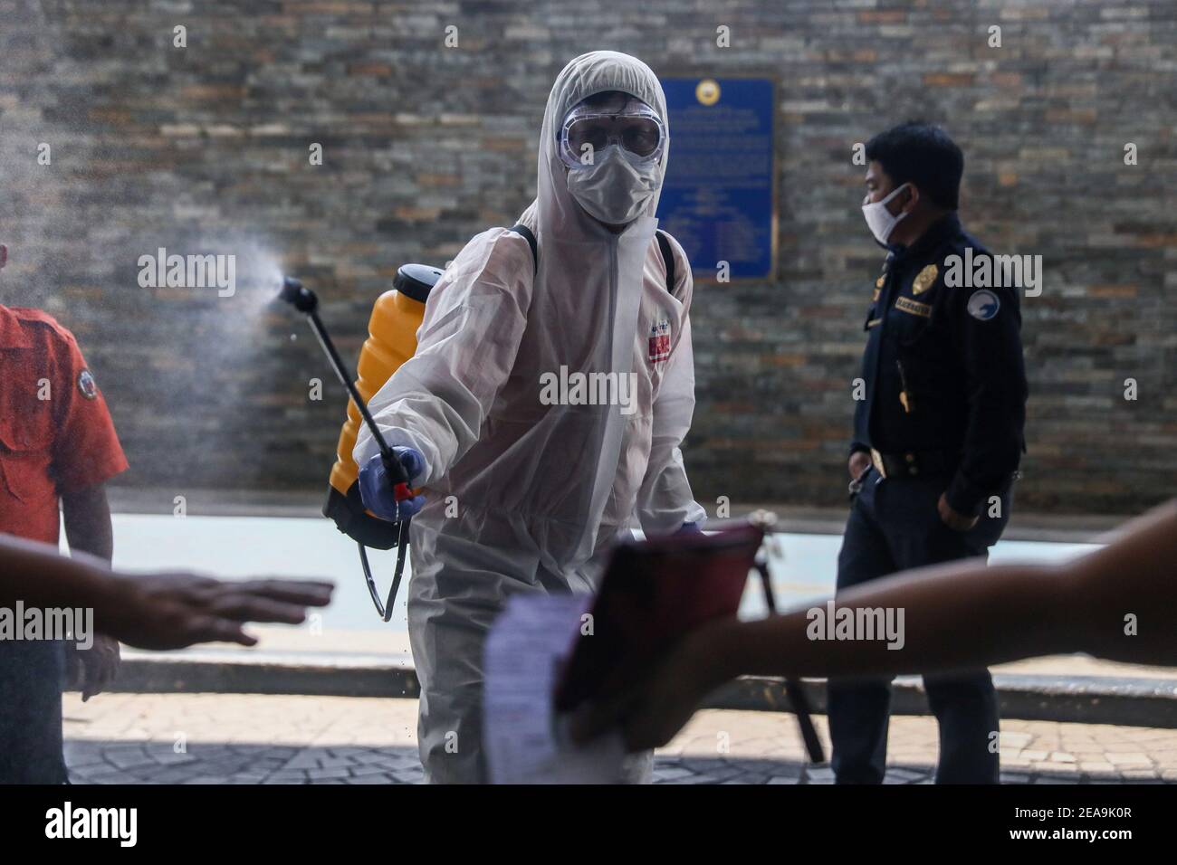 Ein Arbeiter desinfiziert Menschen, die mitten in der Coronavirus-Pandemie in Pasig City, Metro Manila, Philippinen, in das Rathaus eintreten. Stockfoto